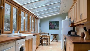 A kitchen with wooden cabinets, a washing machine, a dining table with chairs, and a painting on the wall. - Charming 19th century house on the port of Dahouet (3 *) (Pléneuf-Val-André)