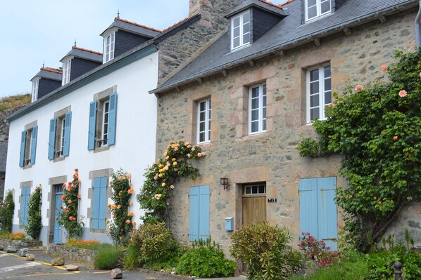 A row of stone buildings with blue shutters and a stone wall with a wooden door. - Charming 19th century house on the port of Dahouet (3 *) (Pléneuf-Val-André)