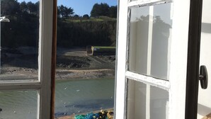 A room with a large window overlooking a body of water, a view of trees, and a construction site in the distance. - Charming 19th century house on the port of Dahouet (3 *) (Pléneuf-Val-André)