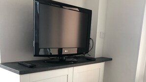 Tasainen näyttö, jossa on valkoinen televisio, ja kaukosäädin on asetettu tasolle.