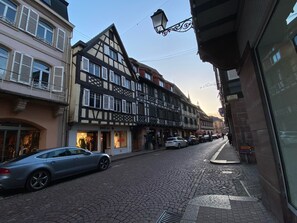 A cobblestone street lined with traditional half-timbered buildings, a parked car, and a street lamp. - Apartment and garden in house in Obernai (Obernai)