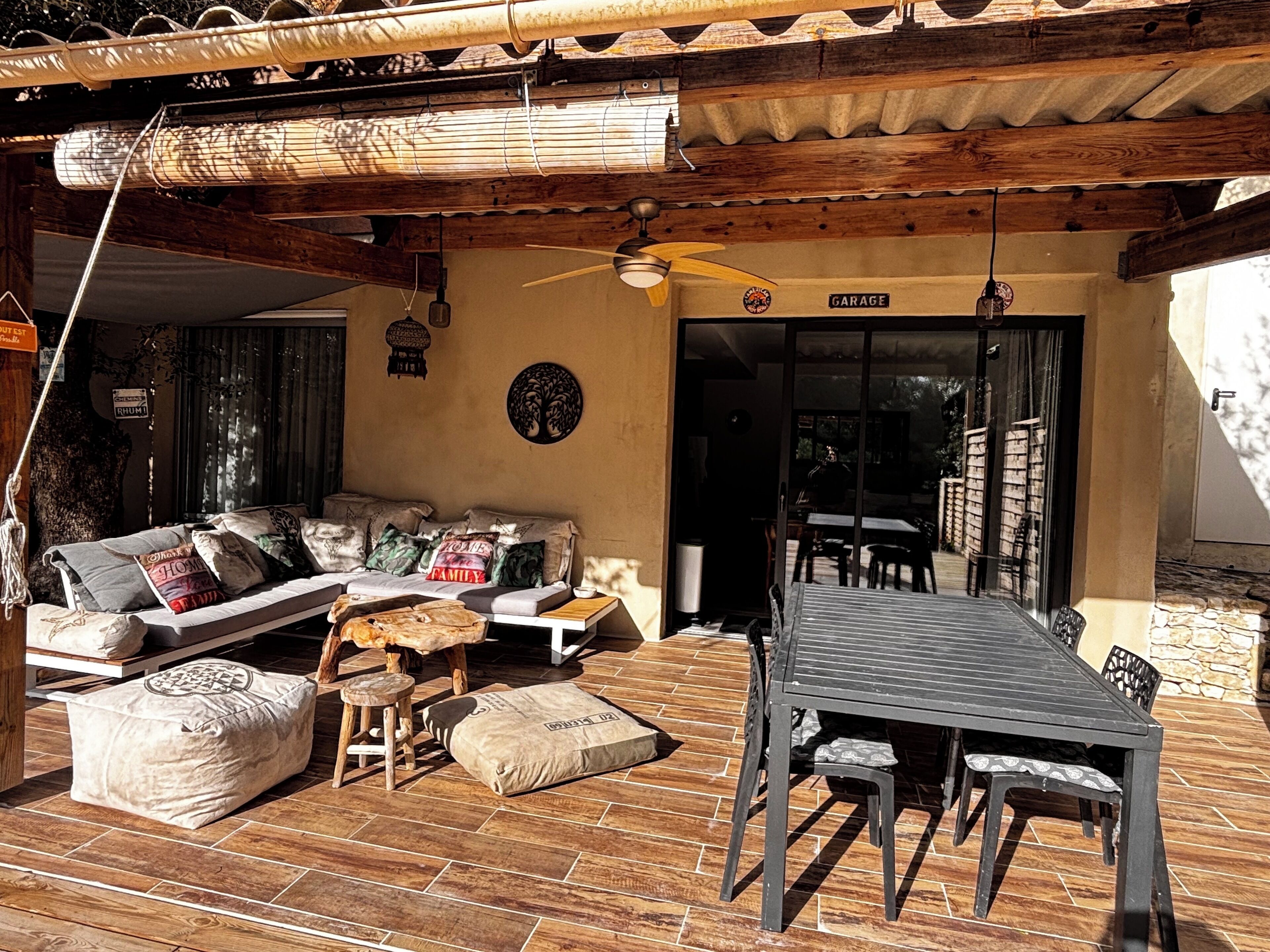 A covered outdoor seating area with a sofa, cushions, and a table.