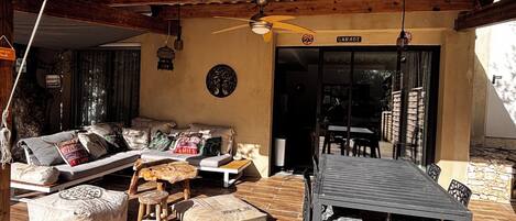 A covered outdoor seating area with a sofa, cushions, and a table.