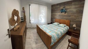 Een slaapkamer met een houten bed, een nachtkastje, een dressoir en een scooter decoratie aan de muur.