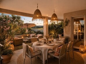 Un área de comedor al aire libre con una mesa redonda dispuesta para cuatro personas, rodeada de sillas.