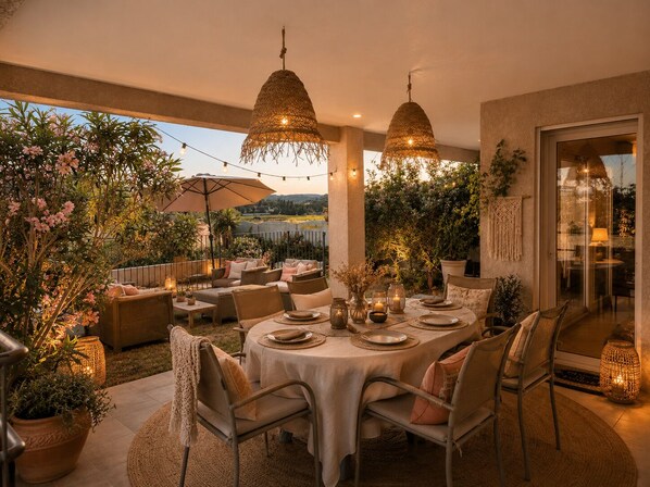 Un área de comedor al aire libre con una mesa redonda dispuesta para cuatro personas, rodeada de sillas.