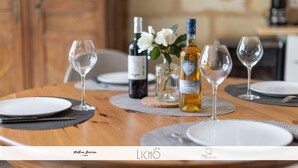 Een eettafel gedekt met wijnglazen, borden en flessen, met een houten tafel en een vaas met bloemen.