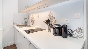 A kitchen with a white countertop, stainless steel sink, and a coffee maker.