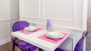 A dining table with pink placemats, white plates, and clear glasses.
