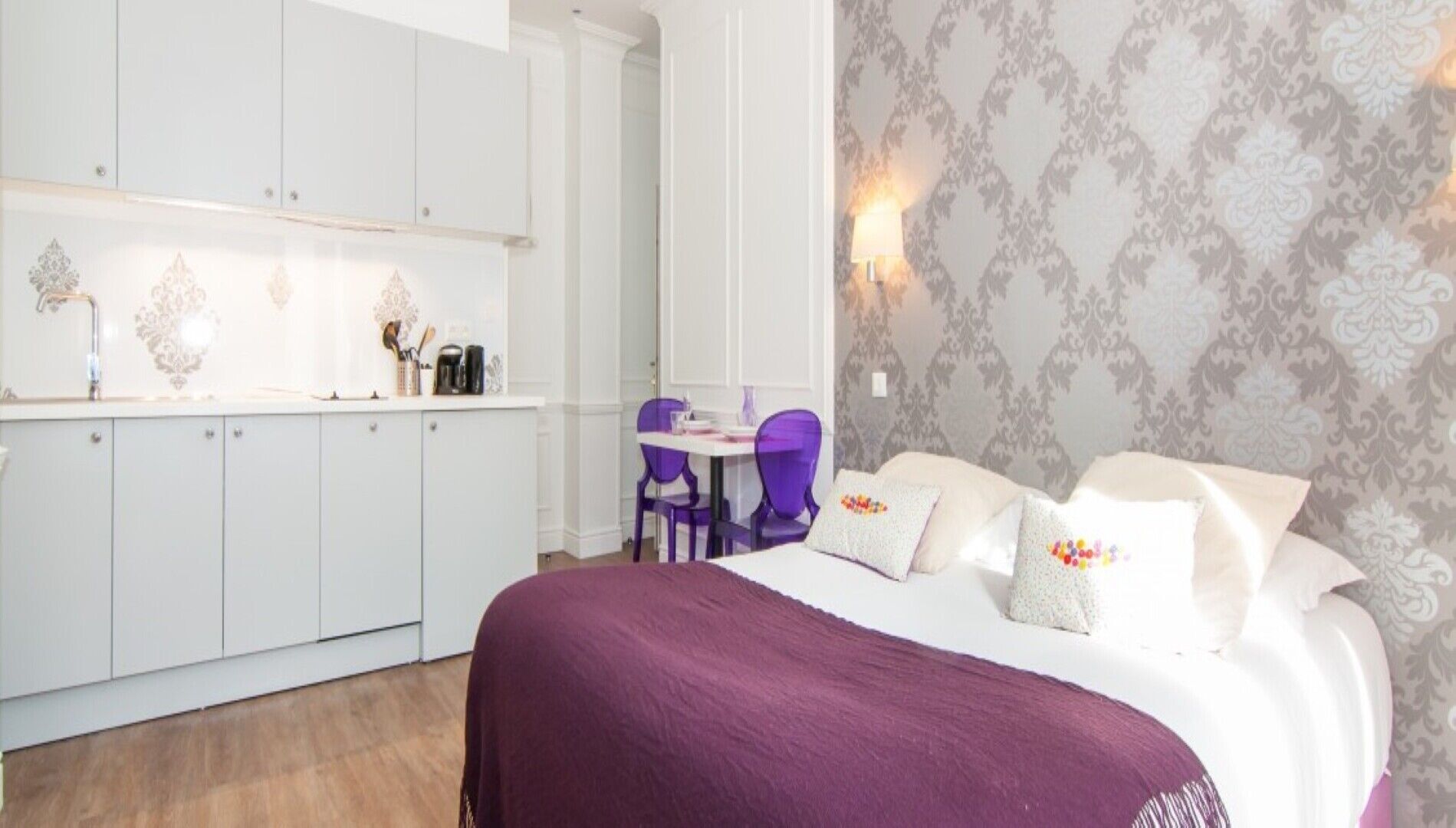 A bedroom with a bed, pillows, a nightstand, and a desk with a chair.