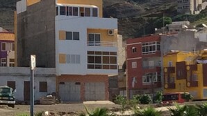 A multi-story building with a flat roof and a mix of window styles. - Apartment for rent. on the island of Sao Vicenter Mindelo near the beach (Mindello)