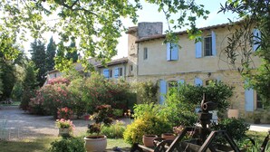 A rustic stone building with a garden featuring potted plants and a water pump.