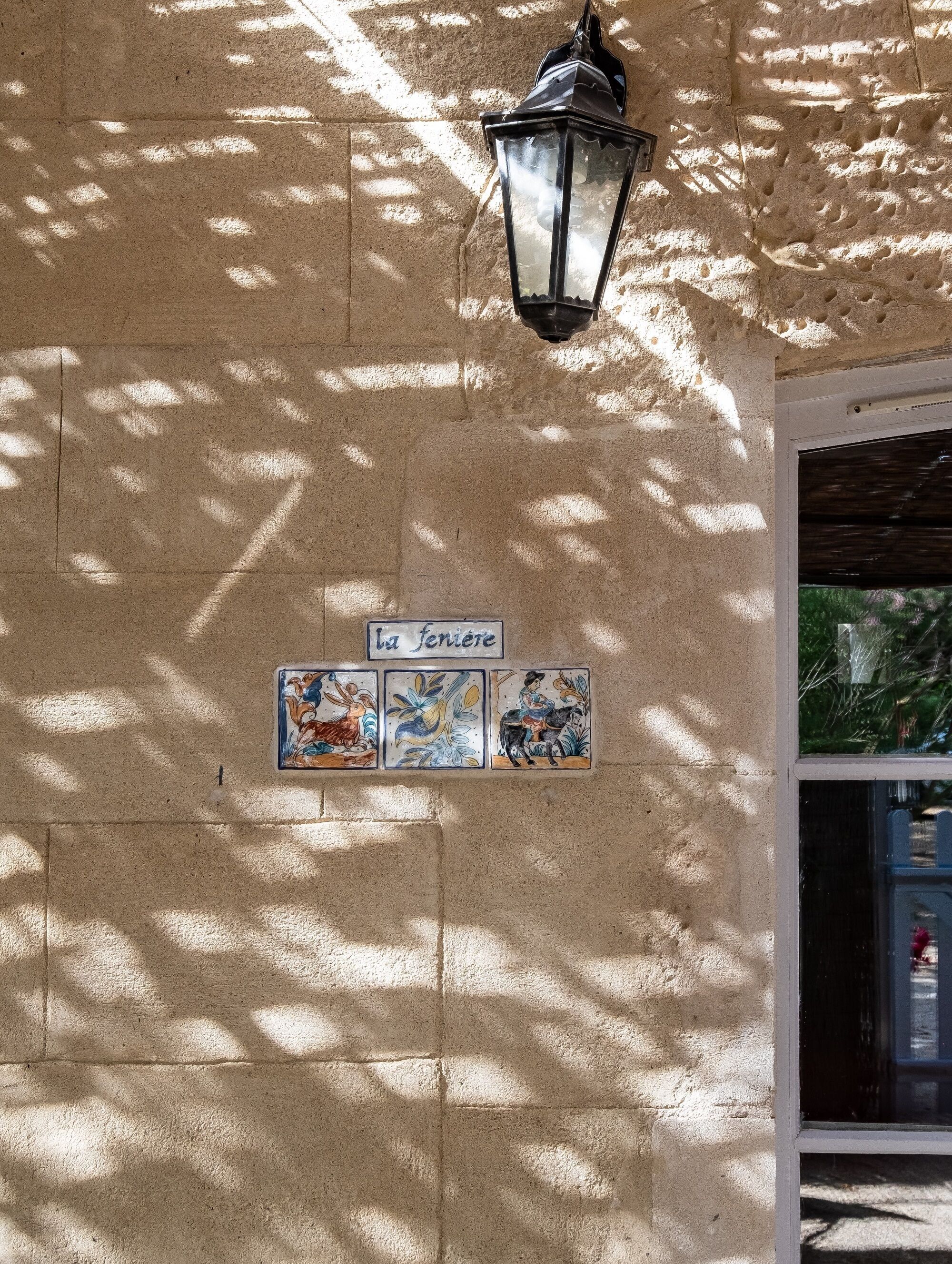 A textured wall with a street lamp and a sign reading "la fenice".