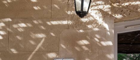 A textured wall with a street lamp and a sign reading "la fenice".