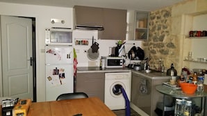 Eine kleine Küche mit Waschmaschine, Mikrowelle und einer Essecke.