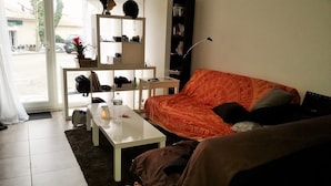 Ein Wohnzimmer mit einem weißen Couchtisch, einem orangefarbenen Sofa und einer weißen Regaleinheit.