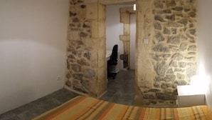 Ein Zimmer mit einer Steinsäule, einem Streifenmuster-Teppich und einem Bett.