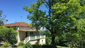 A house with a red-tiled roof, a balcony, and a large tree in the foreground. - white stone cottage in the countryside, with swimming pool. Magnificent view (PORTE-DU-QUERCY)