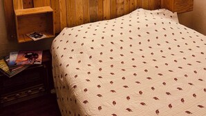 A bedroom with a wooden headboard, a bedside table, and a bed with a patterned quilt. - white stone cottage in the countryside, with swimming pool. Magnificent view (PORTE-DU-QUERCY)