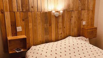 Une chambre à coucher avec une tête de lit en bois, une table de chevet et un lit recouvert d’une courtepointe à motifs.