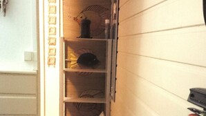 A narrow hallway with a wooden wall and a shelf unit containing various items. - T2 INDIANA air-conditioned, DESHAIES 350 m Grande Anse, 2/3 people, large terrace.  (Deshaies)