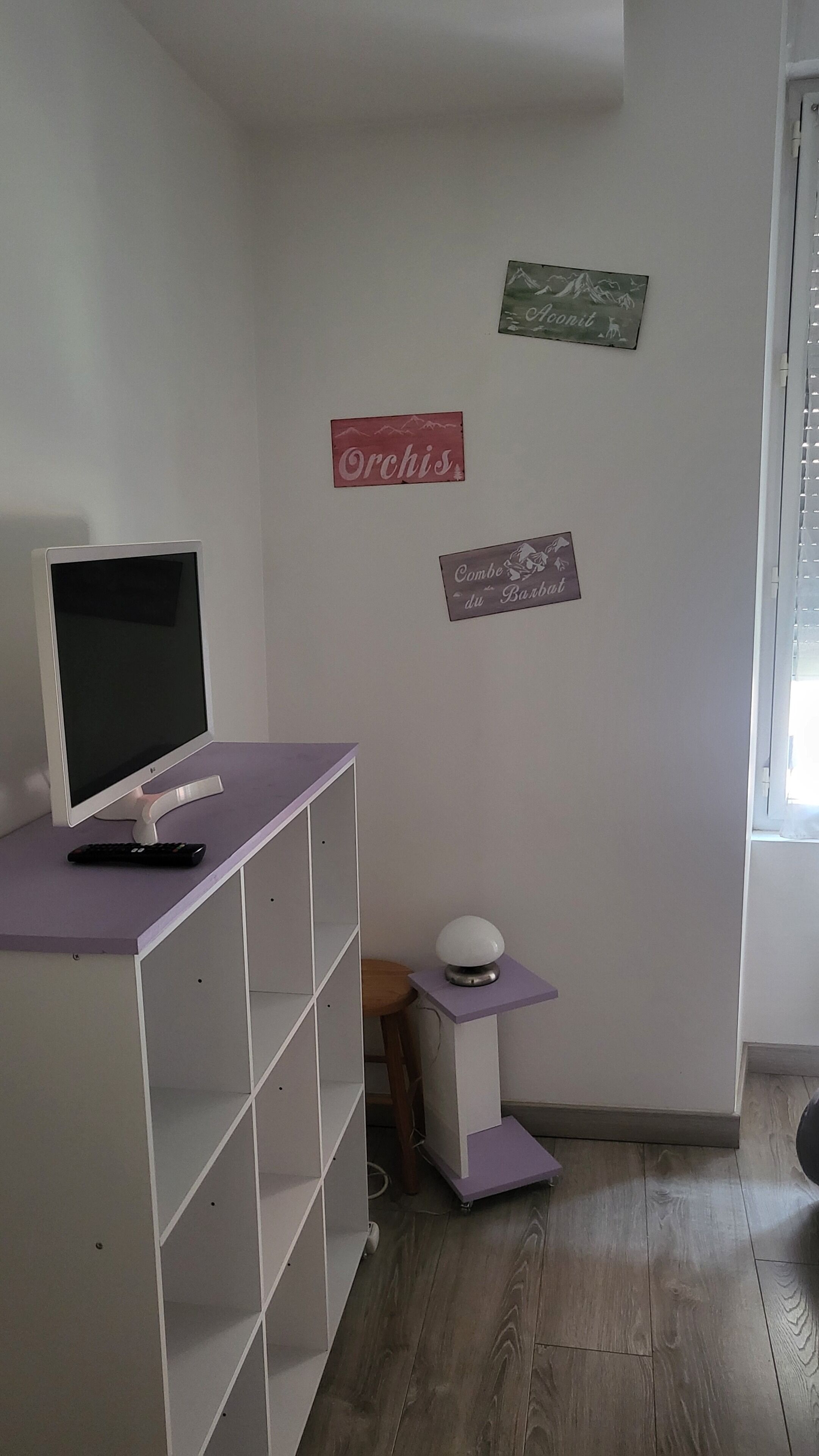 A room with a white desk, a computer monitor, a keyboard, and a small table with a spherical object on it.