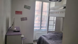 A bedroom with a bunk bed, a desk with a computer, and a window with a view. - Spacious 3-room apartment in the center of the village (Cauterets)