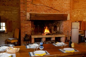 A dining area with a brick fireplace, wooden table, and chairs.