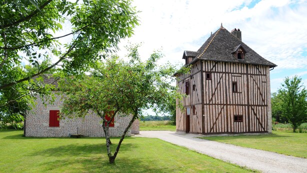 Un bâtiment traditionnel à colombages, avec un chemin de gravier menant à l’entrée.