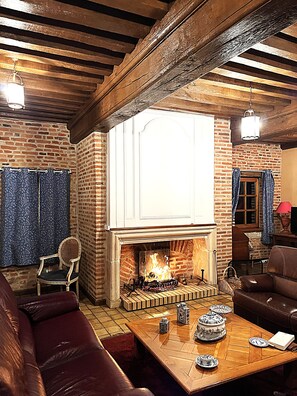 A cozy living room with a fireplace, leather furniture, and a brick wall.