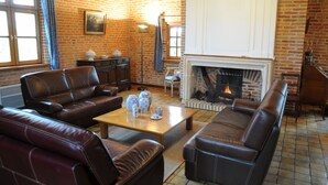 Un salon chaleureux avec des canapés en cuir, une table basse en bois et une cheminée en briques.