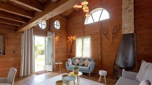 A cozy wooden cabin interior with a sofa, a small table, and a fireplace.