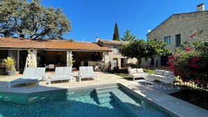 A pool area with lounge chairs, a stone building, and a clear blue sky.