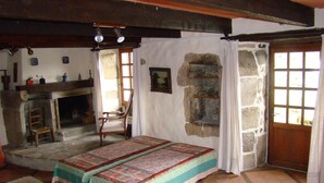 Une pièce rustique avec un lit, une cheminée et un mur en pierre.