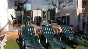 Un patio con sillones de jardín verdes, una mesa de comedor y sillas.