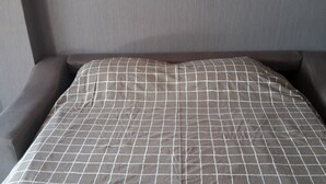 Una cama con un edredón a cuadros y un cabecero.