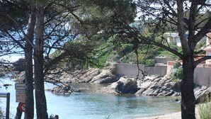 Une zone côtière caractérisée par un rivage rocheux, une route et un panneau indiquant la présence d’une plage.