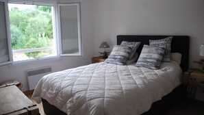 Une chambre à coucher avec un grand lit, une fenêtre, une table de chevet et une lampe.