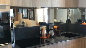 Une cuisine moderne avec des meubles en bois, un plan de travail noir et une machine à café.