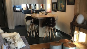 Un salon moderne avec un canapé, un tapis à motifs zébrés et un coin cuisine à l’arrière-plan.
