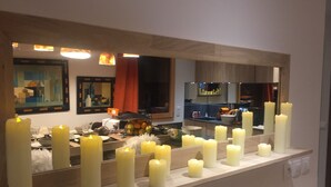 Une salle de bain avec un grand miroir, de nombreuses bougies et un panier de fruits posé sur le comptoir.