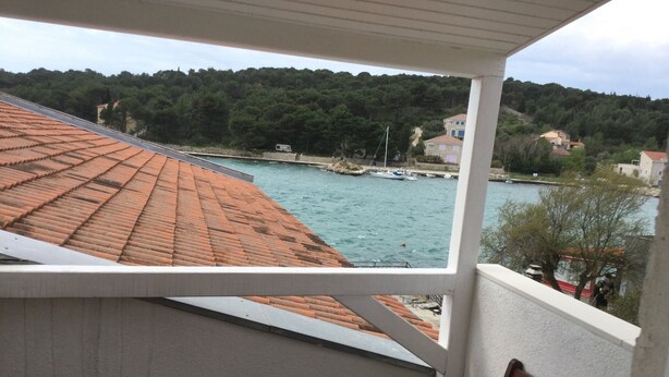 A balcony with a view of a body of water, boats, and a forested hillside. - PRVINSKI AKVAREL, large renovated fisherman's house adapted for disabled visitors  (Prvić Luka)