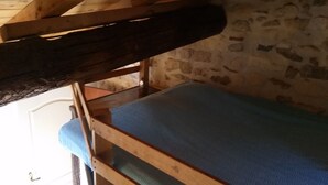 Uma cama beliche com colchão azul num quarto com paredes de pedra.