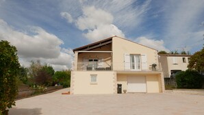 Un edificio a due piani con un balcone, un garage e una facciata in pietra.