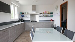 Una cucina moderna con isola centrale, elettrodomestici integrati e zona pranzo con tavolo in vetro.
