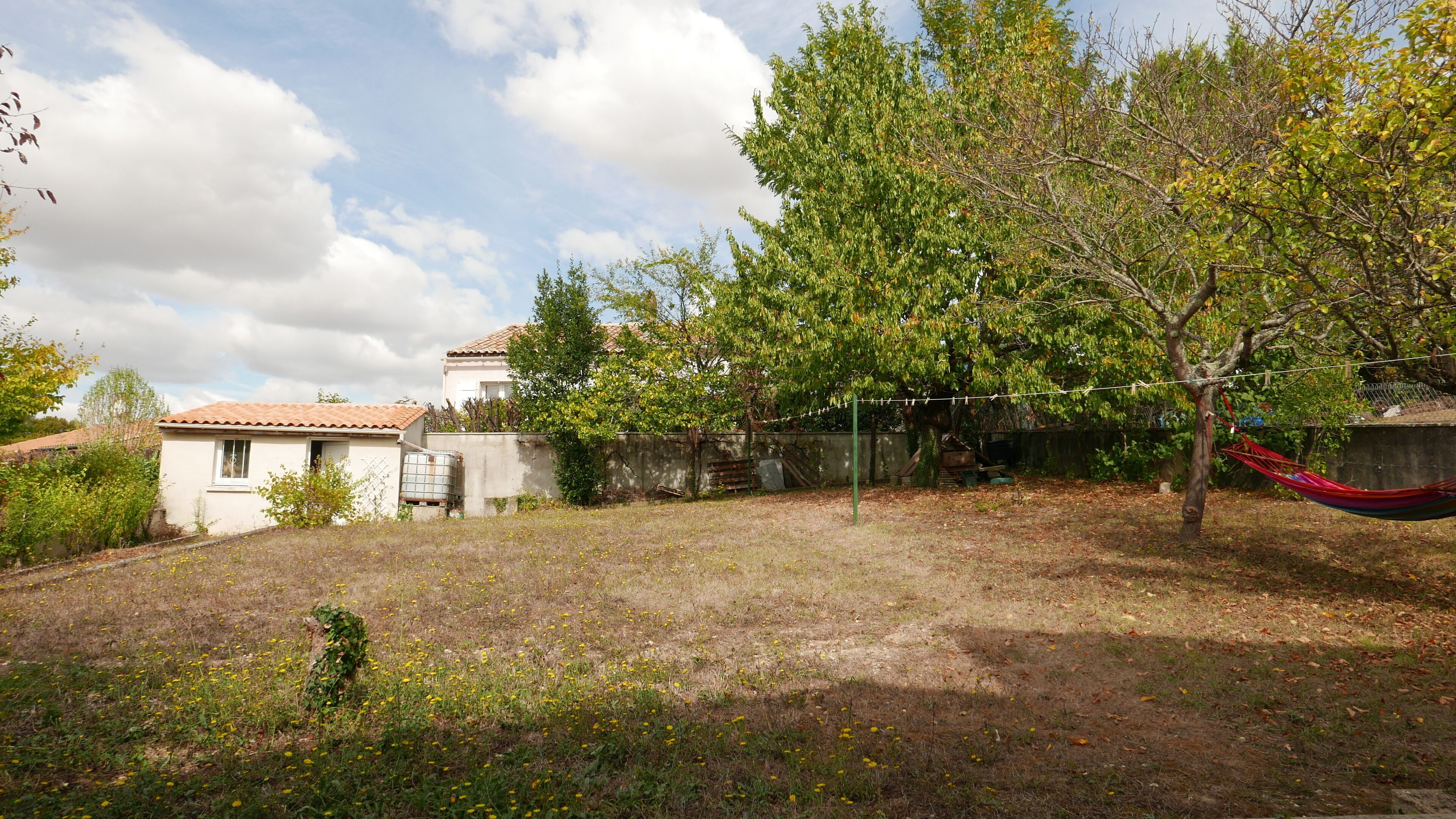 Un barrio residencial con una casa, una hamaca y un patio cubierto de césped.