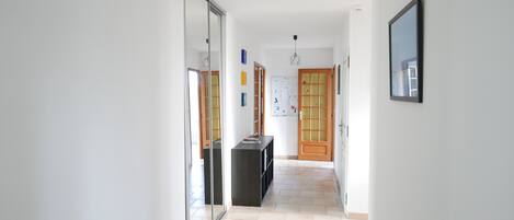 A hallway with a tiled floor, a black storage unit, and a wooden door with glass panels.
