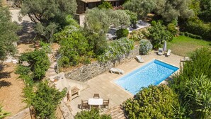 Uma villa com piscina, área de estar ao ar livre e jardim de oliveiras.