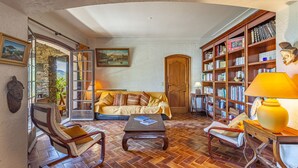Uma sala de estar aconchegante com um sofá, duas poltronas, uma mesinha de centro e uma estante de livros.