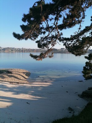 A beach with clear water, a sandy shore, and a distant town. - MOBILE HOME ON PRIVATE GROUND (Landéda)